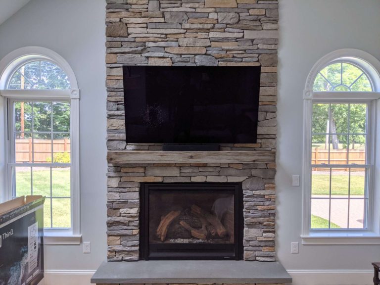 TV mounted above a fireplace on a stone surface.